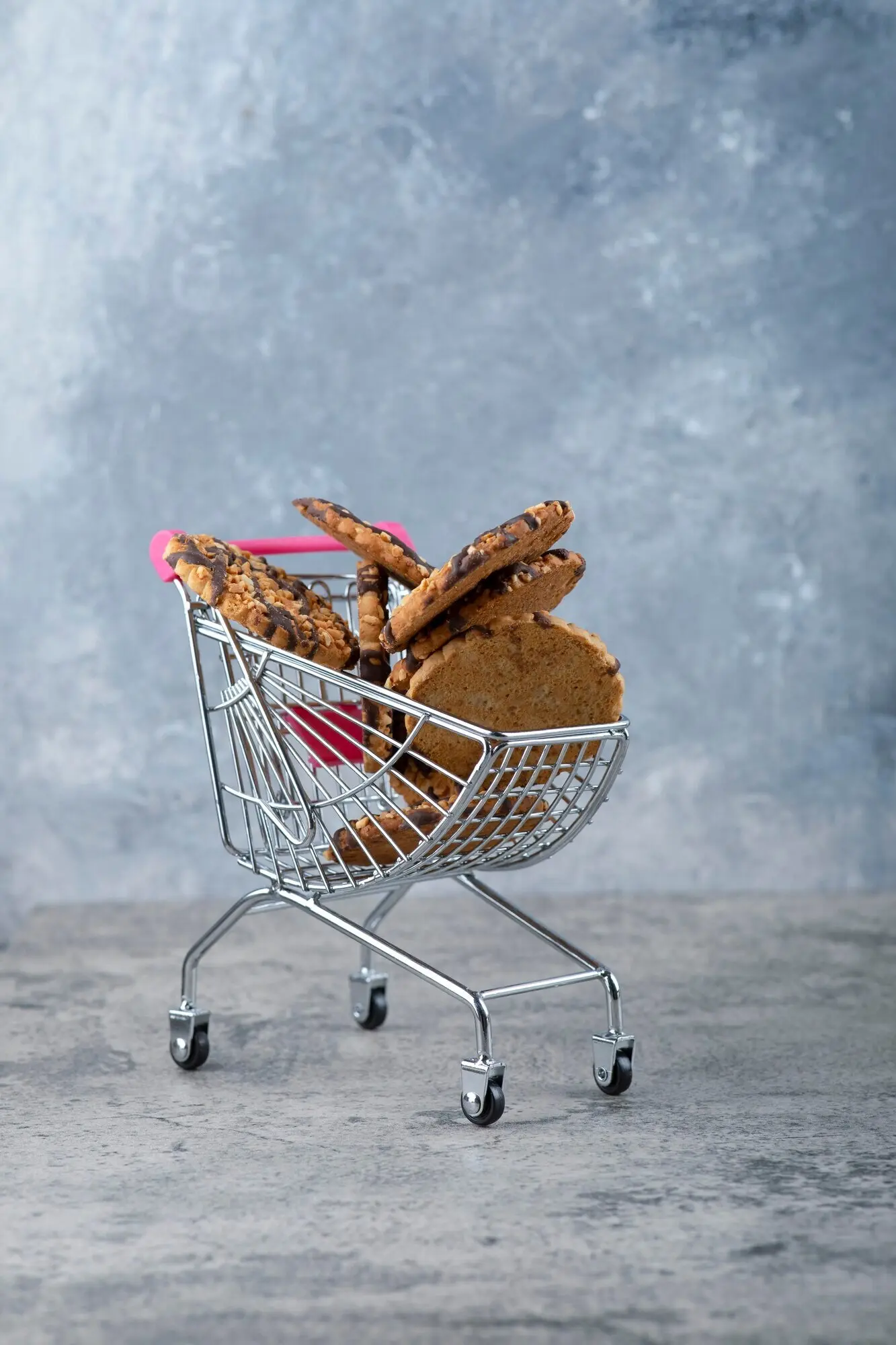 Auf einem Marmortisch steht ein kleiner pinker Wagen mit leckeren Keksen.